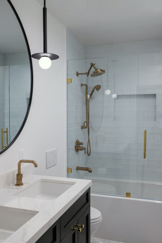 Inspiration for a bathroom in San Francisco with black cabinets, an alcove tub, a shower/bathtub combo, a wall-mount toilet, blue tile, glass tile, white walls, marble floors, an undermount sink, engineered quartz benchtops, grey floor, a hinged shower door, white benchtops, a niche and a double vanity.
