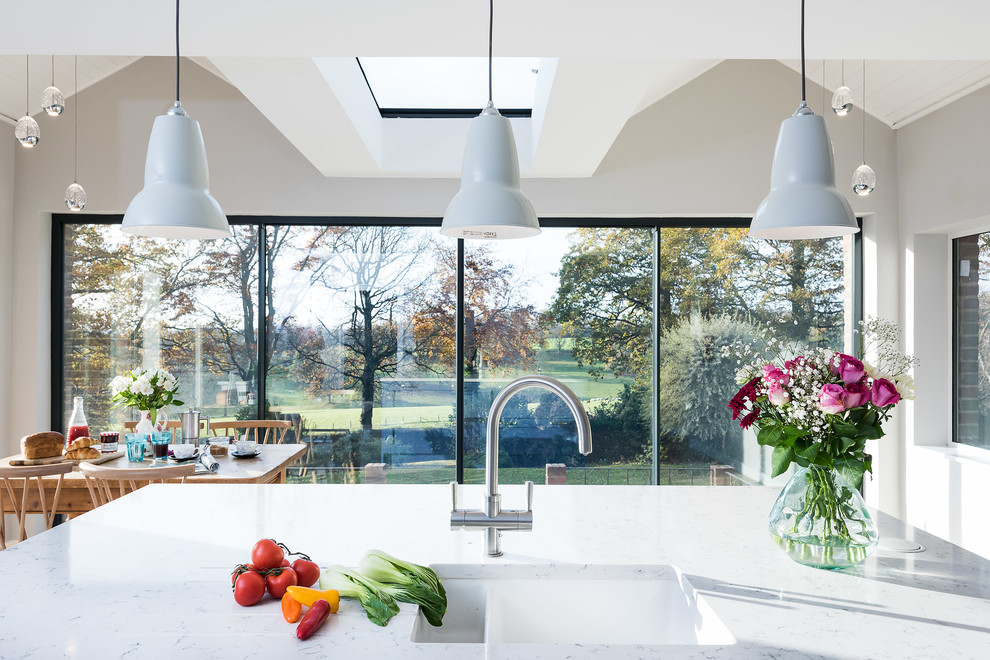 This is an example of a large transitional single-wall open plan kitchen in Buckinghamshire with a double-bowl sink, shaker cabinets, blue cabinets, quartzite benchtops, white splashback, subway tile splashback, black appliances, porcelain floors, with island, beige floor and yellow benchtop.