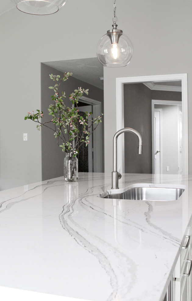 Example of a mid-sized transitional single-wall eat-in kitchen design in Toronto with an undermount sink, raised-panel cabinets, white cabinets, marble countertops, white backsplash, stainless steel appliances and an island