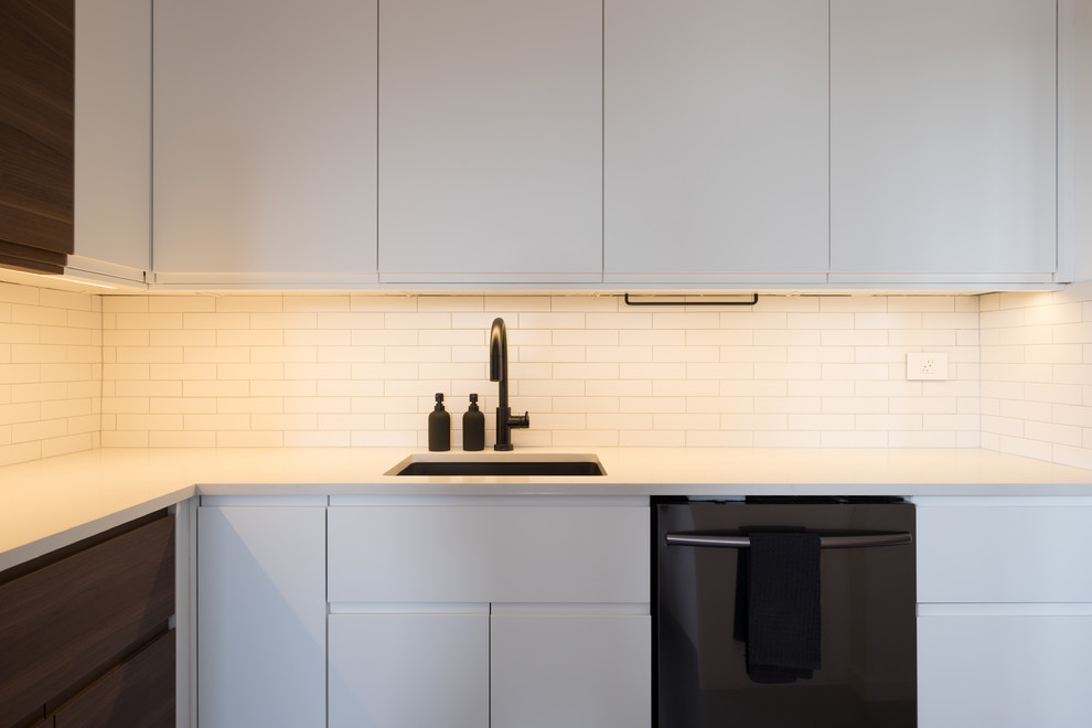 Design ideas for a small contemporary u-shaped kitchen in New York with an undermount sink, flat-panel cabinets, white cabinets, quartz benchtops, white splashback, subway tile splashback, black appliances, concrete floors, no island and grey floor.
