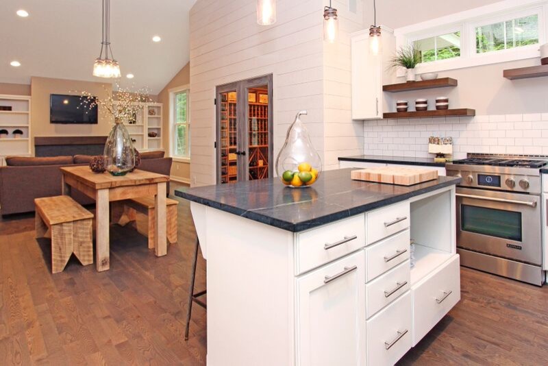 Eclectic galley kitchen in Grand Rapids with a farmhouse sink, raised-panel cabinets, white cabinets, soapstone benchtops, white splashback, subway tile splashback, stainless steel appliances, medium hardwood floors and with island.