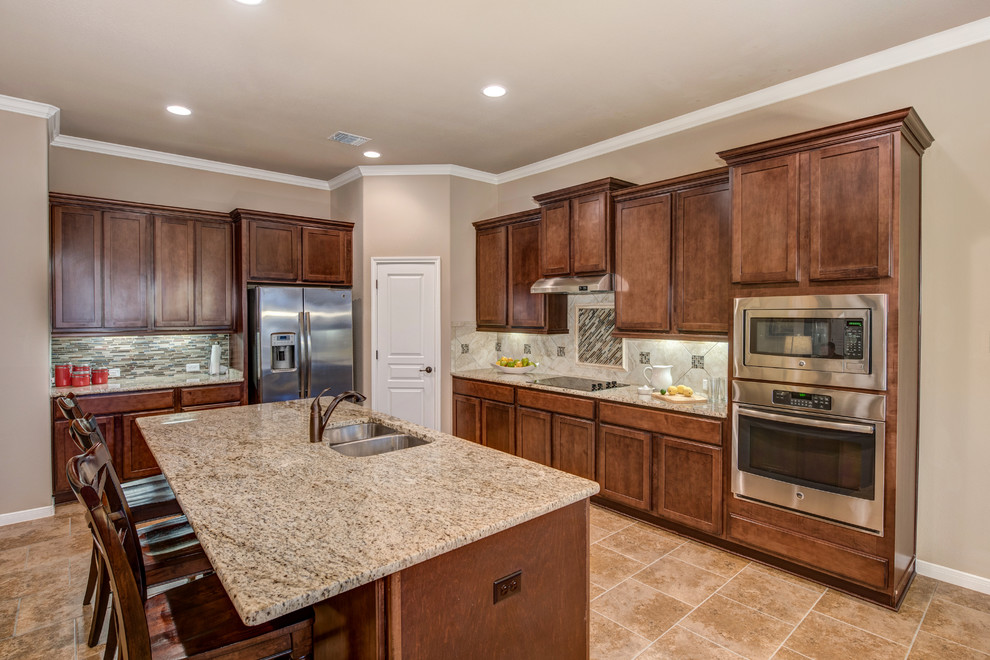 Photo of a mid-sized transitional l-shaped open plan kitchen in Austin with an undermount sink, raised-panel cabinets, medium wood cabinets, granite benchtops, glass tile splashback, stainless steel appliances, ceramic floors, with island and beige splashback.