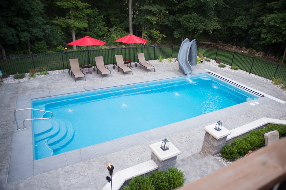Photo of a large modern backyard rectangular pool in Other with a water slide and stamped concrete.