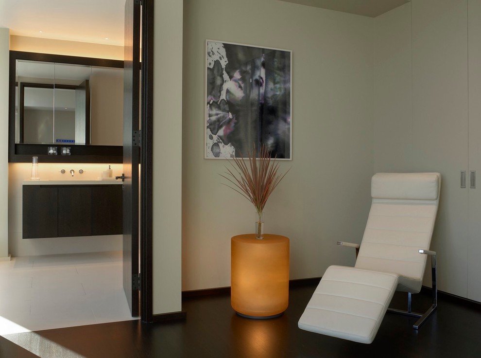 This is an example of a contemporary bedroom in New York with white walls and dark hardwood floors.