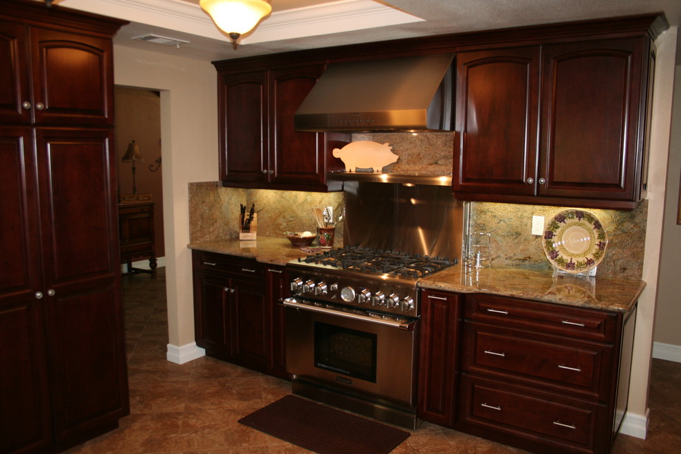 Inspiration for a large transitional u-shaped kitchen remodel in Orange County with raised-panel cabinets, dark wood cabinets and stainless steel appliances