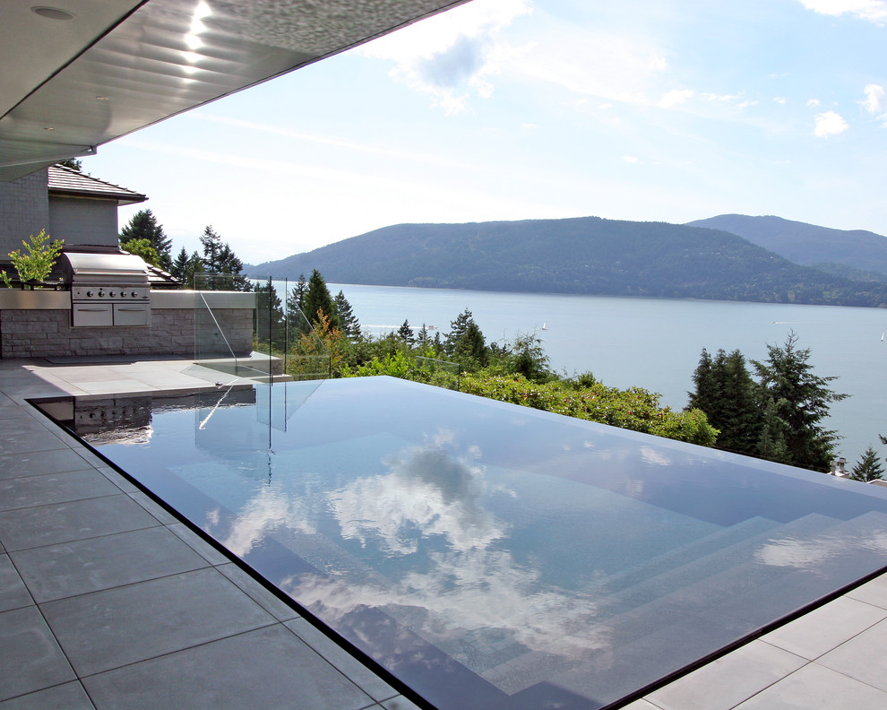 This is an example of a mid-sized contemporary backyard rectangular infinity pool in Vancouver.