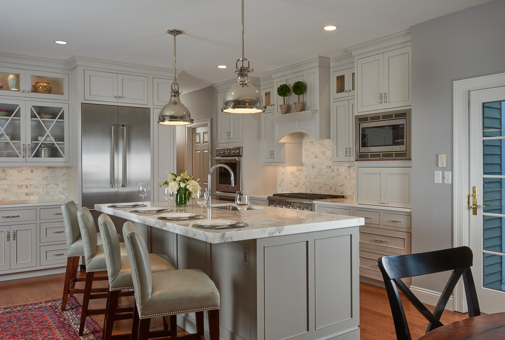 Mid-sized transitional l-shaped eat-in kitchen in Boston with an undermount sink, beaded inset cabinets, white cabinets, marble benchtops, grey splashback, marble splashback, stainless steel appliances, medium hardwood floors, with island, brown floor and white benchtop.
