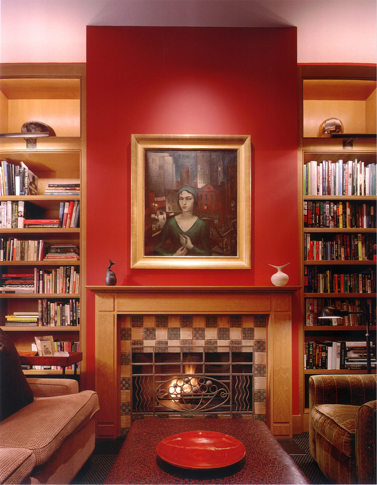 This is an example of a mid-sized transitional loft-style living room in New York with a library, red walls, carpet, a standard fireplace, a tile fireplace surround and no tv.