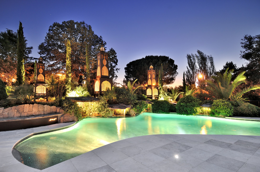 Design ideas for a large tropical custom-shaped lap pool in Madrid with concrete pavers.