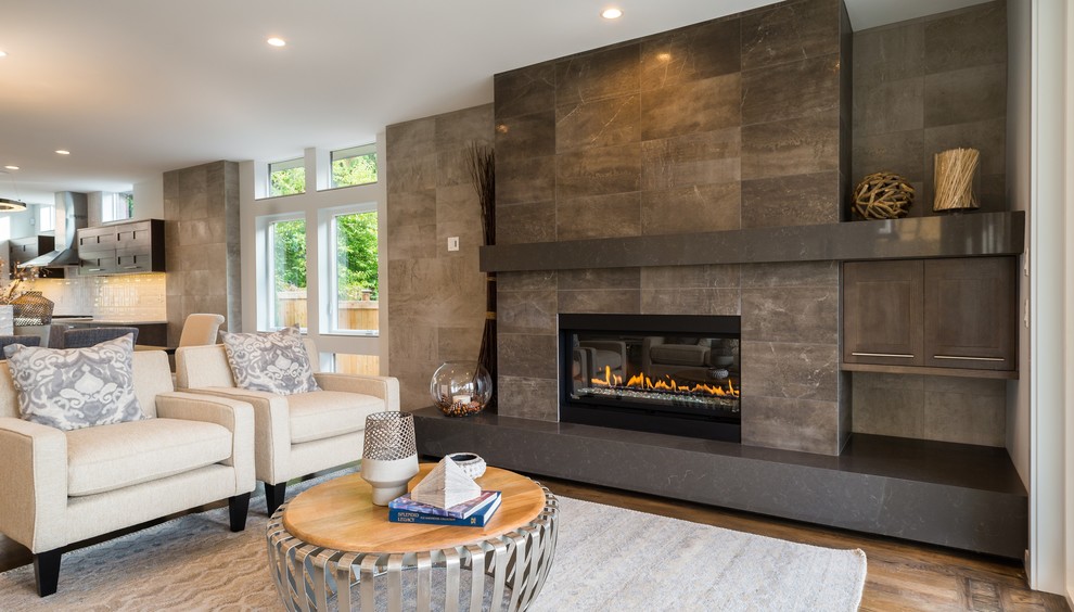 Photo of a mid-sized contemporary open concept family room in Seattle with medium hardwood floors, a standard fireplace, a tile fireplace surround, no tv and brown floor.