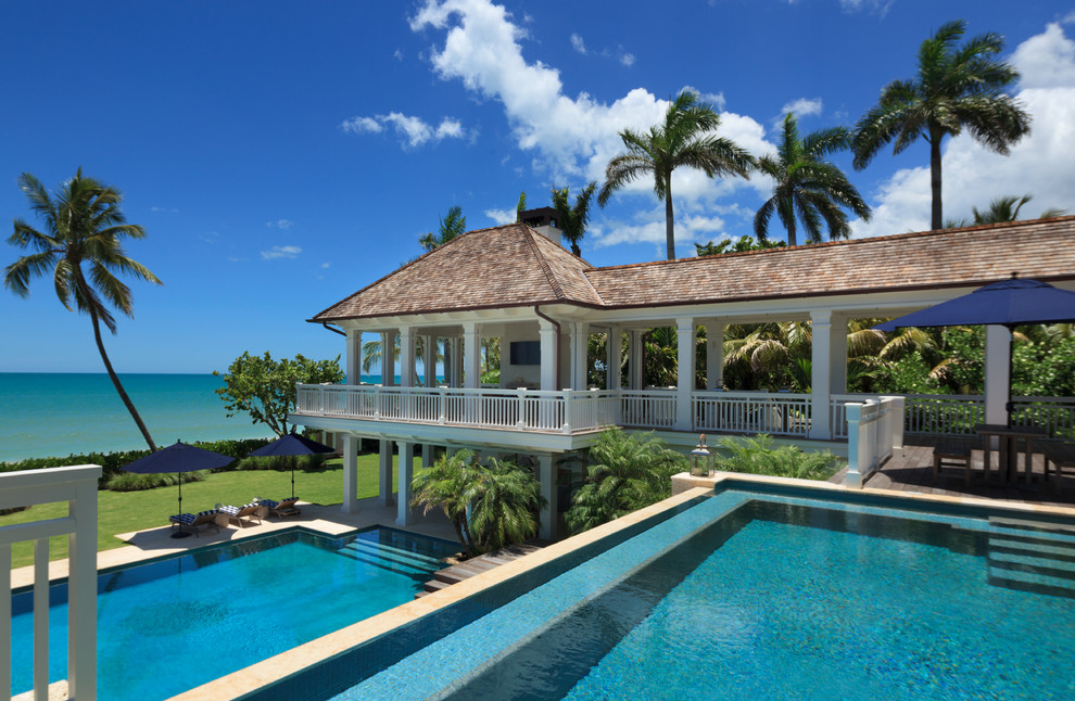 Design ideas for an expansive beach style backyard custom-shaped infinity pool in Miami with natural stone pavers.