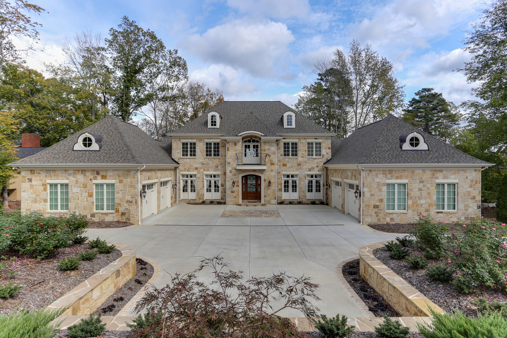 This is an example of an expansive traditional three-storey beige exterior in Raleigh with stone veneer and a hip roof.