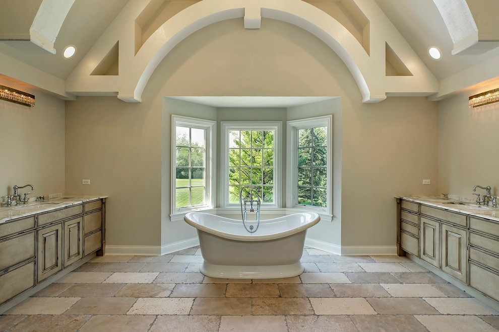 This is an example of a mid-sized country master bathroom in Chicago with raised-panel cabinets, medium wood cabinets, a freestanding tub, a one-piece toilet, beige walls, an undermount sink, slate floors and marble benchtops.