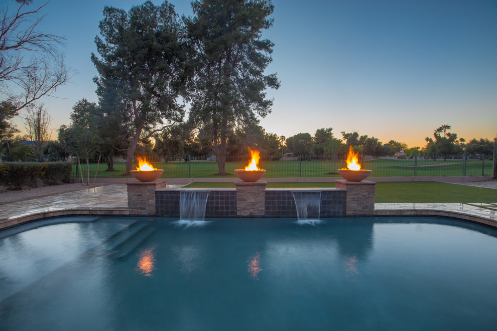 Design ideas for a large mediterranean backyard custom-shaped pool in Phoenix with a water feature and tile.