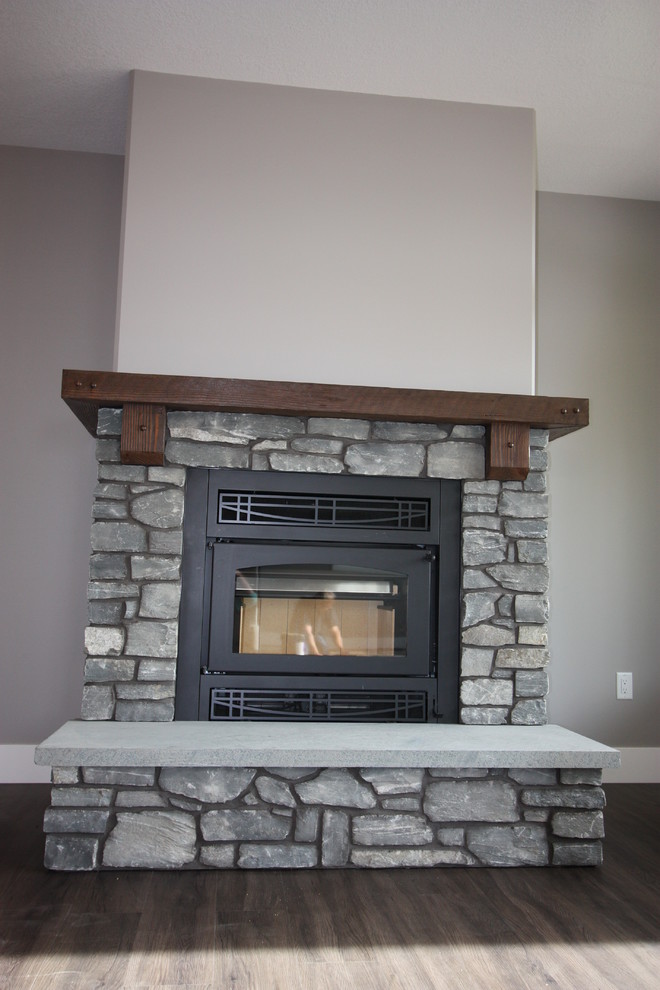 Photo of a traditional living room in Calgary with a wood stove and a stone fireplace surround.