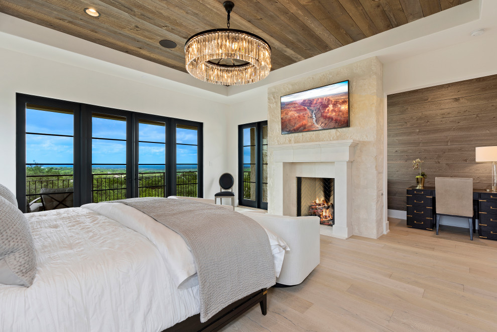 Geräumiges Hauptschlafzimmer mit weißer Wandfarbe, hellem Holzboden, Kamin, Holzdecke und Ziegelwänden in Sonstige