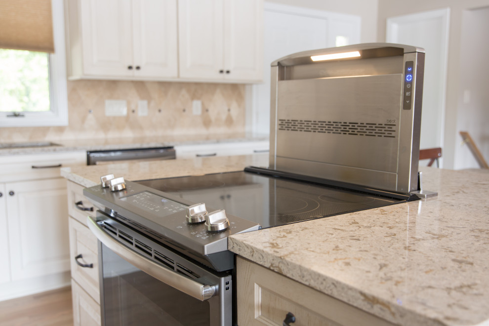 Inspiration for a transitional l-shaped light wood floor eat-in kitchen remodel with an undermount sink, raised-panel cabinets, white cabinets, beige backsplash, stainless steel appliances, an island and beige countertops