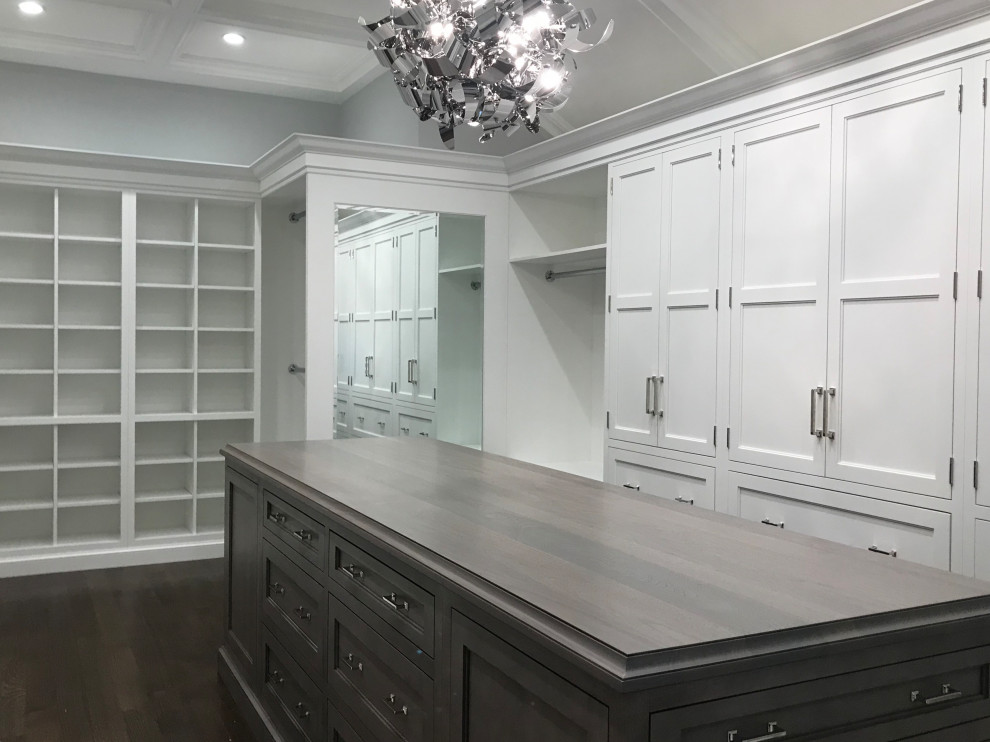 This is an example of a large transitional walk-in wardrobe in New York with recessed-panel cabinets, dark wood cabinets, dark hardwood floors, brown floor and recessed.
