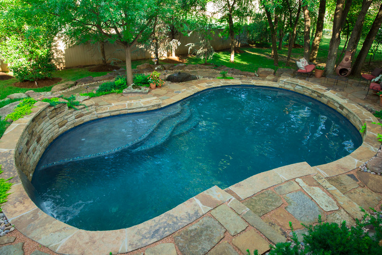 Photo of a large transitional backyard custom-shaped natural pool in Oklahoma City with a water feature and natural stone pavers.