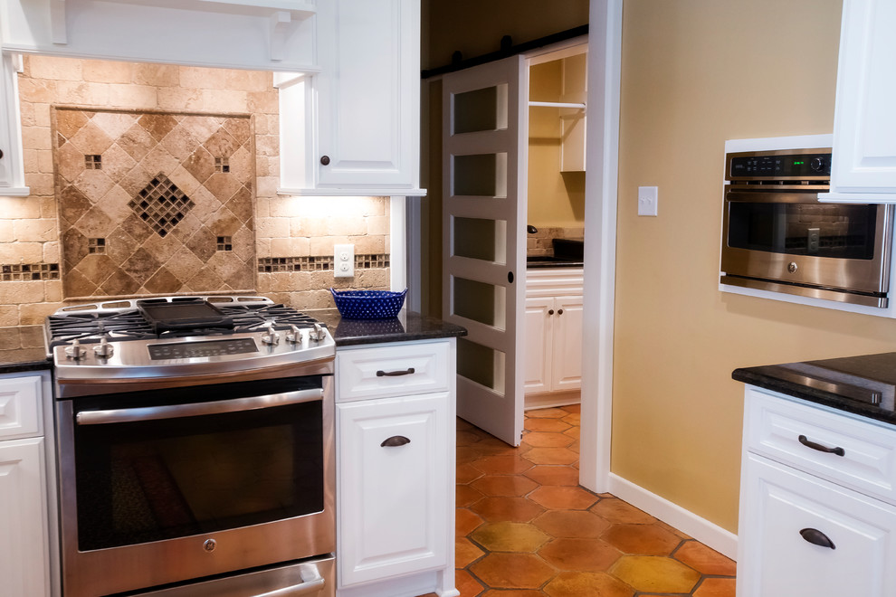 Kitchen - large transitional terra-cotta tile kitchen idea in Austin with raised-panel cabinets, white cabinets, granite countertops, multicolored backsplash, stone tile backsplash and stainless steel appliances