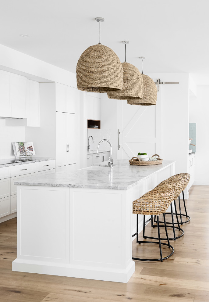 Immagine di una cucina costiera di medie dimensioni con ante bianche e top in marmo