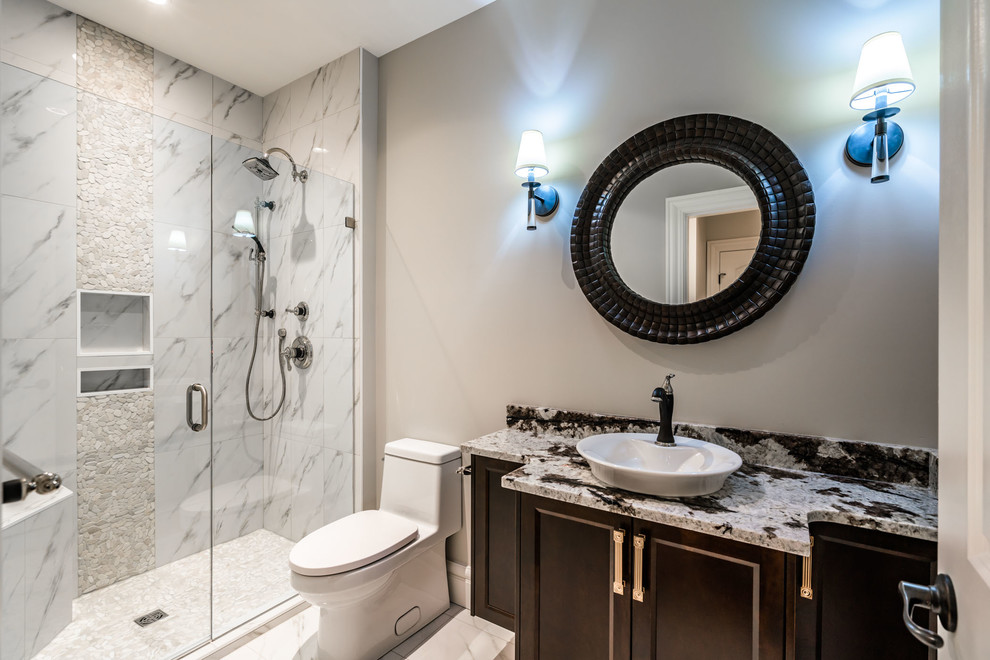 Inspiration for a mid-sized transitional bathroom in Other with furniture-like cabinets, dark wood cabinets, a one-piece toilet, grey walls, marble floors, a vessel sink, granite benchtops, white floor, multi-coloured benchtops, an alcove shower, gray tile, white tile, marble and a hinged shower door.