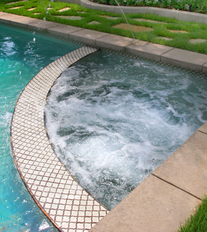 This is an example of a large mediterranean backyard custom-shaped lap pool in Los Angeles with a water feature and concrete pavers.
