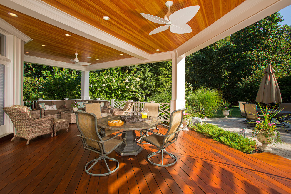 This is an example of an expansive tropical backyard deck in DC Metro with an outdoor kitchen and a pergola.