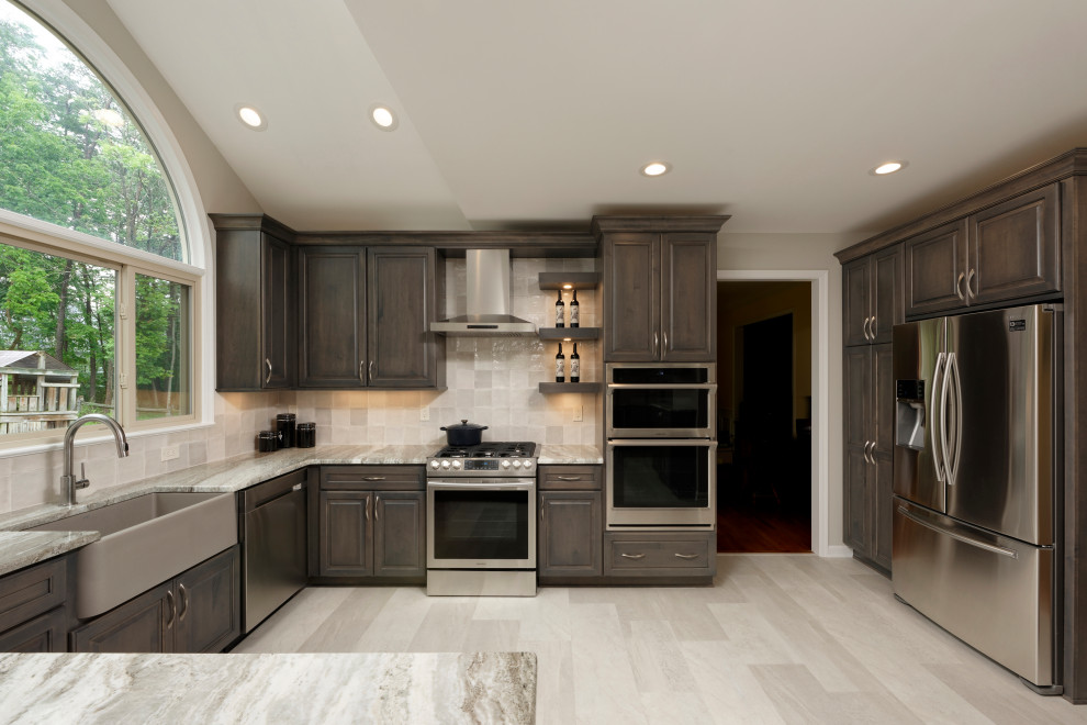 Transitional eat-in kitchen in DC Metro with a farmhouse sink, raised-panel cabinets, dark wood cabinets, quartzite benchtops, grey splashback, porcelain splashback, stainless steel appliances, vinyl floors, with island, grey floor and multi-coloured benchtop.