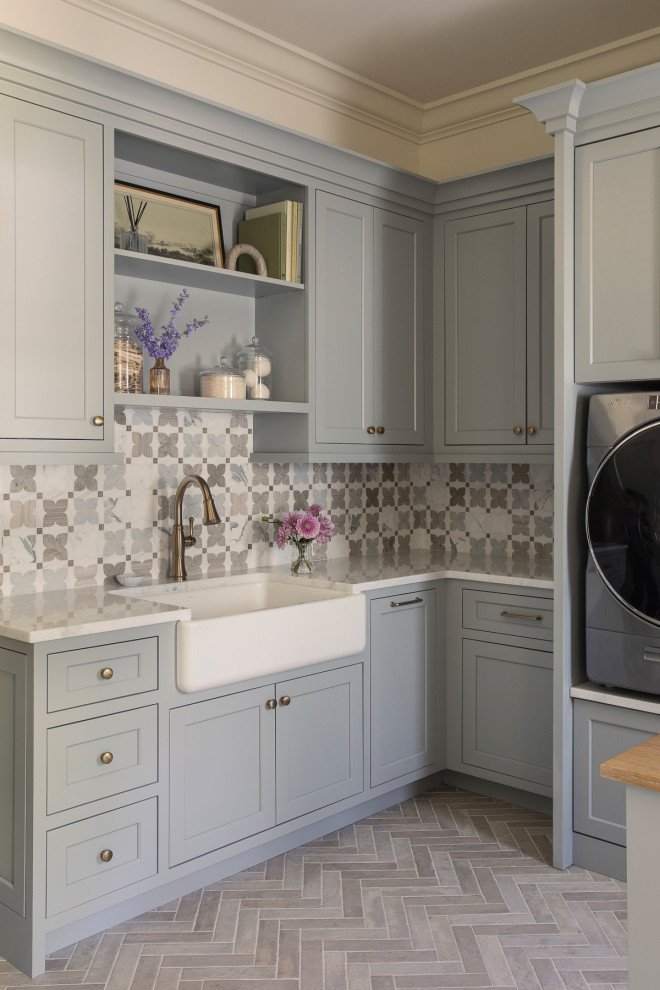 Inspiration for a large transitional l-shaped gray floor laundry room remodel in St Louis with a farmhouse sink, gray cabinets, quartz countertops, a side-by-side washer/dryer, white countertops, shaker cabinets and gray walls
