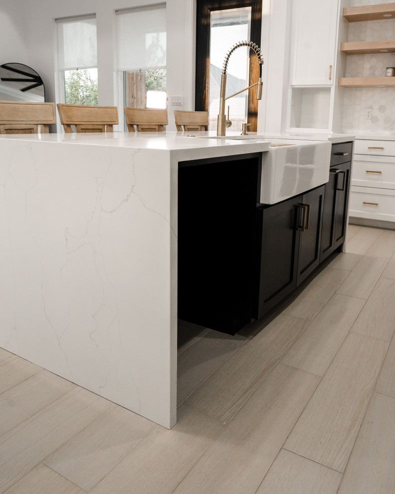 Design ideas for a small modern l-shaped eat-in kitchen in Austin with a farmhouse sink, shaker cabinets, white cabinets, quartzite benchtops, white splashback, porcelain splashback, stainless steel appliances, light hardwood floors, with island, grey floor and white benchtop.