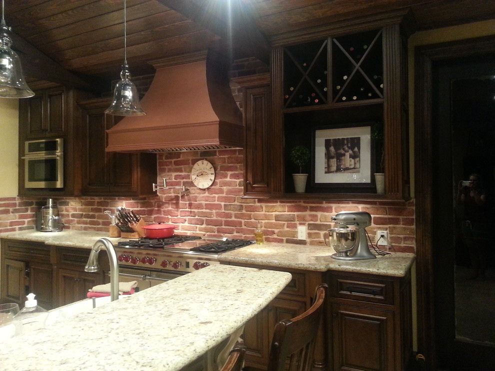 Large mountain style u-shaped porcelain tile eat-in kitchen photo in Houston with an undermount sink, raised-panel cabinets, dark wood cabinets, granite countertops, red backsplash, brick backsplash, stainless steel appliances and two islands