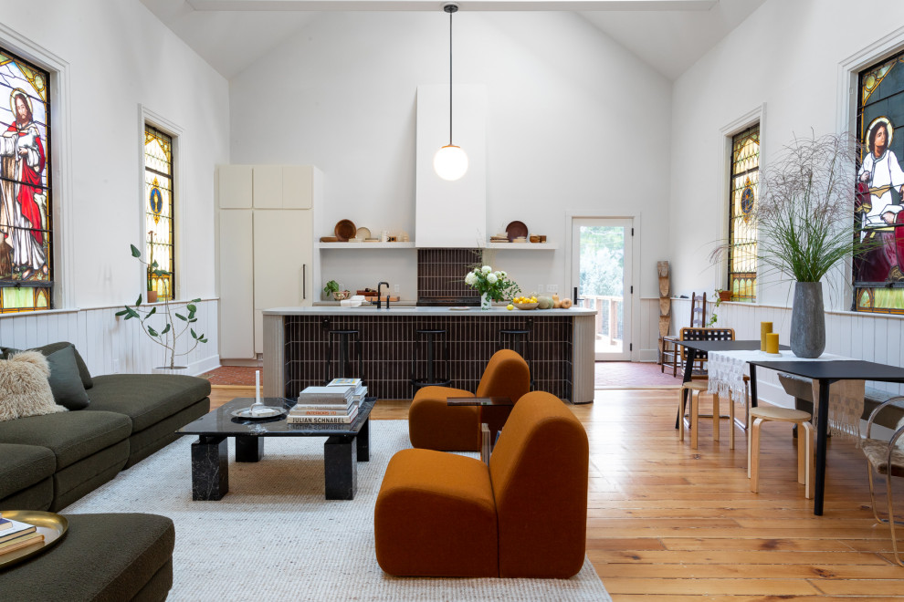 Trendy open concept medium tone wood floor, brown floor and vaulted ceiling living room photo in Milwaukee with white walls