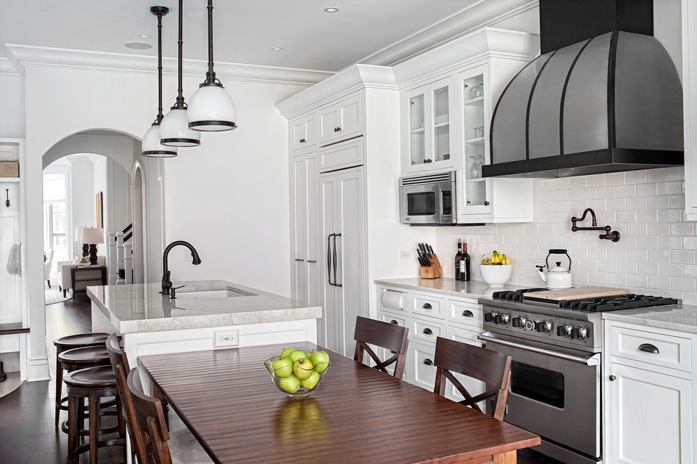 Inspiration for a large traditional galley eat-in kitchen in Chicago with white cabinets, quartzite benchtops, white splashback, subway tile splashback, stainless steel appliances, dark hardwood floors, with island and recessed-panel cabinets.