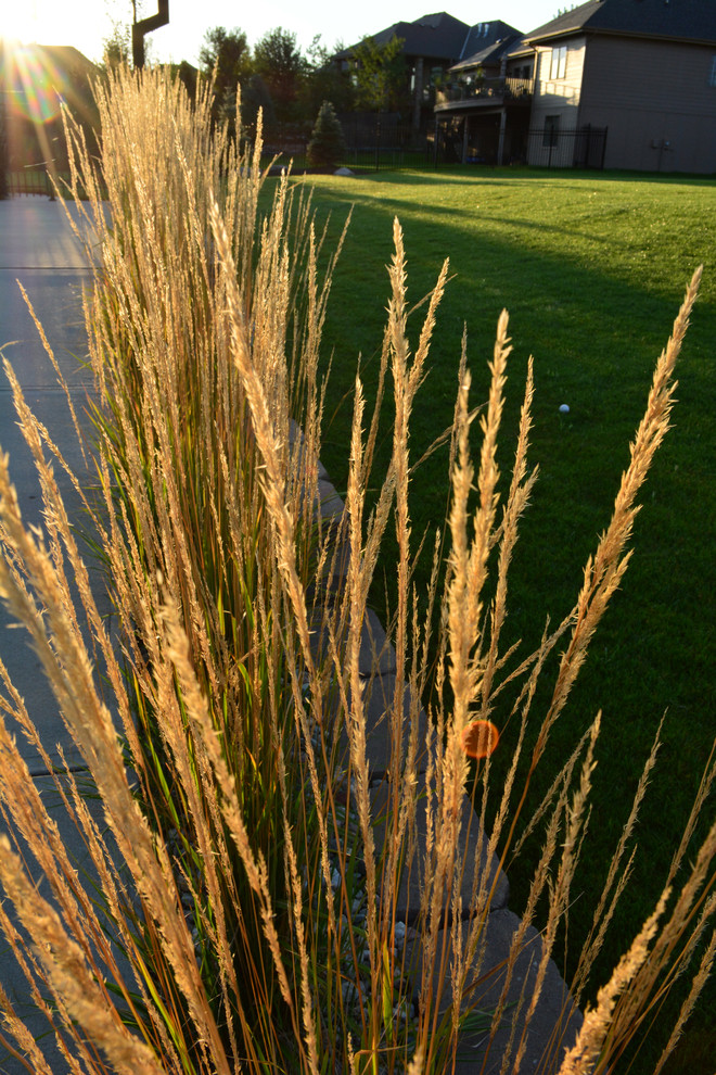 This is an example of a mid-sized rustic partial sun front yard concrete paver landscaping in Omaha.