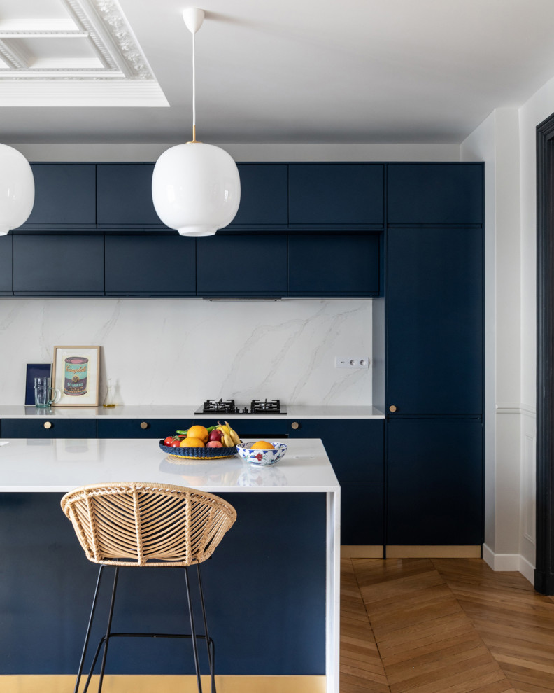 Photo of a large contemporary eat-in kitchen in Paris with light hardwood floors, an undermount sink, flat-panel cabinets, blue cabinets, quartzite benchtops, white splashback, engineered quartz splashback, panelled appliances, with island and white benchtop.