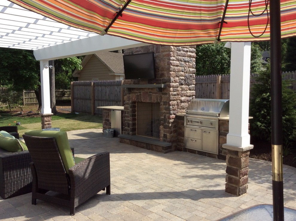 Photo of a large arts and crafts backyard patio in New York with an outdoor kitchen, concrete pavers and a pergola.
