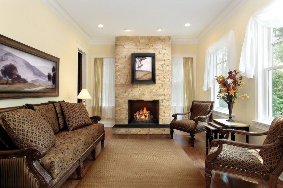 Mid-sized traditional formal enclosed living room in Other with yellow walls, medium hardwood floors, a standard fireplace, a stone fireplace surround, no tv and beige floor.