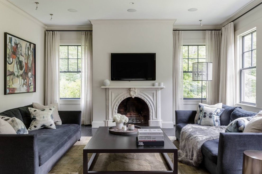 Inspiration for a transitional living room in Boston with beige walls, dark hardwood floors, a standard fireplace, a wall-mounted tv and black floor.