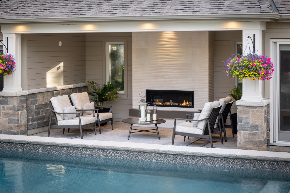 Example of a mid-sized transitional backyard stamped concrete and rectangular pool house design in Toronto