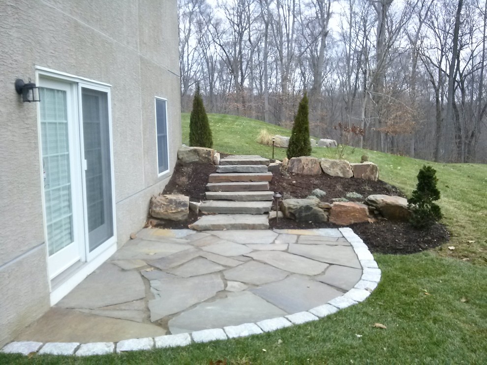 Design ideas for a large traditional backyard full sun garden in Philadelphia with a retaining wall and natural stone pavers.