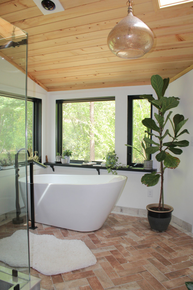 This is an example of a large country master bathroom in Atlanta with flat-panel cabinets, medium wood cabinets, a freestanding tub, a corner shower, a one-piece toilet, white tile, white walls, terra-cotta floors, a vessel sink, granite benchtops, brown floor, a sliding shower screen, beige benchtops, an enclosed toilet, a double vanity, a built-in vanity, wood and brick walls.