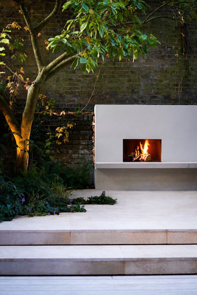 Small contemporary backyard partial sun garden in London with with fireplace and decking.