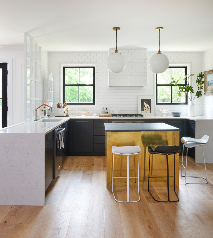 Photo of a contemporary u-shaped kitchen in Other with a single-bowl sink, flat-panel cabinets, white splashback, subway tile splashback, light hardwood floors, with island, beige floor and white benchtop.