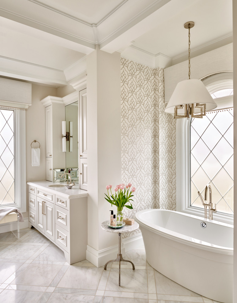 Inspiration for a large mediterranean ensuite bathroom in Phoenix with raised-panel cabinets, white cabinets, a freestanding bath, white walls, a submerged sink, white worktops, a built in vanity unit, a coffered ceiling and wallpapered walls.