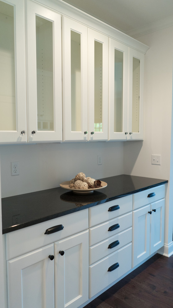 Open concept kitchen - mid-sized transitional l-shaped dark wood floor open concept kitchen idea with an undermount sink, shaker cabinets, white cabinets, granite countertops, gray backsplash, stainless steel appliances and an island