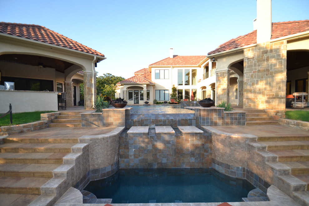 Design ideas for a large eclectic courtyard custom-shaped infinity pool in Dallas with a water feature and stamped concrete.