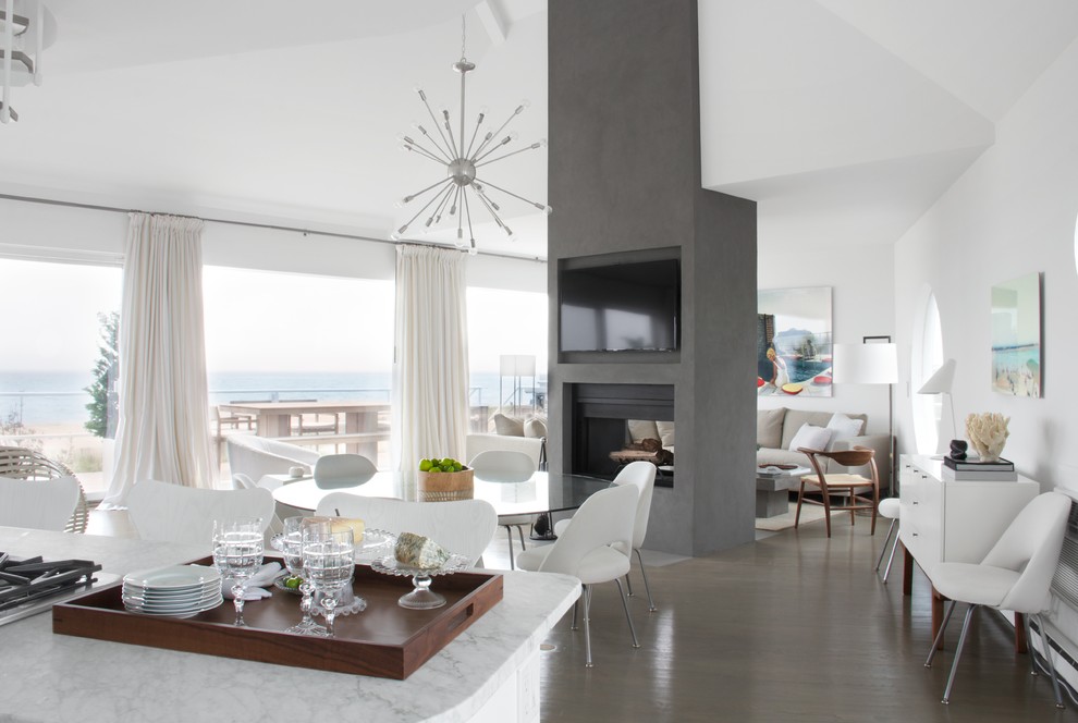 This is an example of a contemporary open plan dining in New York with white walls, medium hardwood floors, a two-sided fireplace and a concrete fireplace surround.