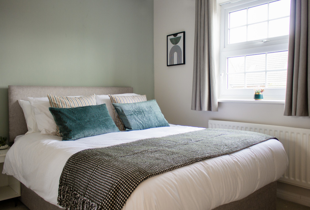 Medium sized contemporary guest bedroom in Gloucestershire with green walls, carpet, beige floors and a feature wall.