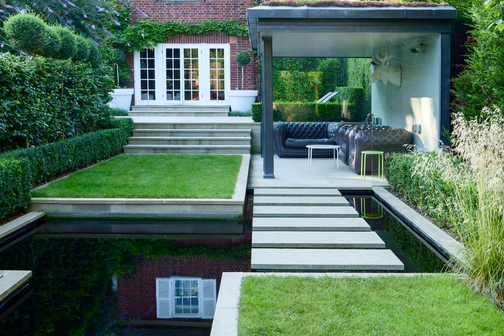Inspiration for a mid-sized contemporary backyard full sun garden in London with natural stone pavers and with pond.